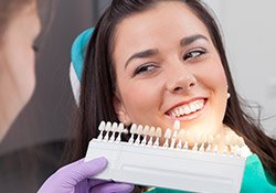 Woman comparing teeth to color shading chart