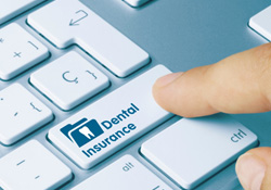 A finger pressing a keyboard button labeled “dental insurance