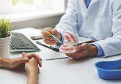 A dentist holding dentures while consulting with a patient