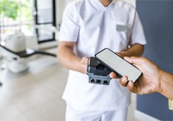 A patient using their phone to pay the cost of dentures