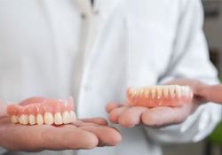 Upper and lower dentures in dentist’s hands 