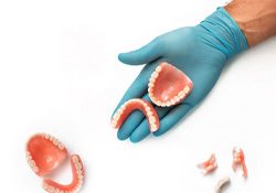 Gloved hand showcasing full and partial dentures