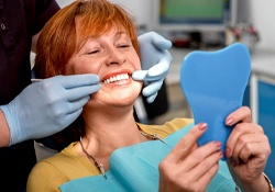 A dentist showing an older female patient how her partial is fitting into her mouth while she looks in the mirror