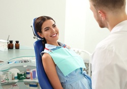 A female patient lying back in a dentist’s chair and smiling at her dentist