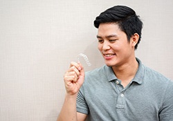 Man holding and looking at an Invisalign tray