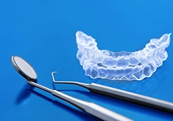 A set of Invisalign aligners and two dental instruments lying next to them on a table