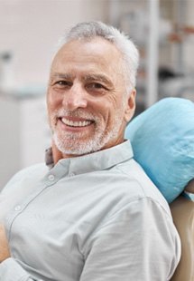 man smiling while holding dental mirror 