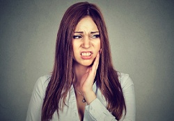 A woman holding her cheek in pain