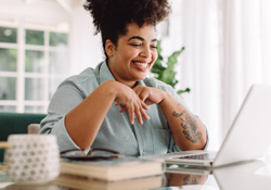 Woman smiling while working on laptop at home