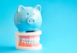 Piggy bank sitting on a set of model teeth