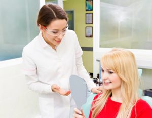 a female patient looking at her smile with her dentist next to her