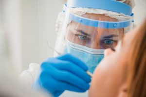 a dentist wearing a face mask and shield while performing treatment on a patient