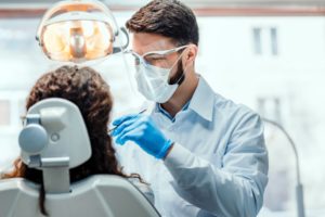 a dentist wearing proper personal protective equipment while treating a female patient