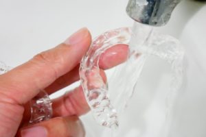 woman cleaning her Invisalign aligner