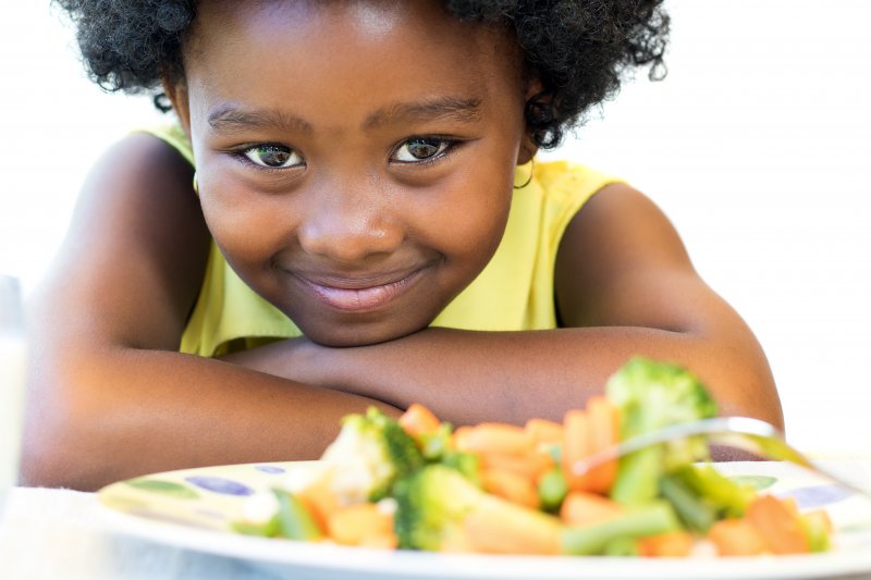 Child eating balanced meal with cooked veggies