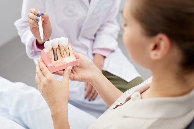 Patient holding a model of dental implants.