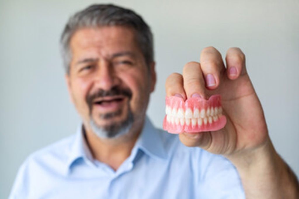 Man holding his dentures.