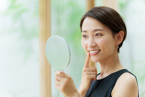 Woman checking smile in a handheld mirror
