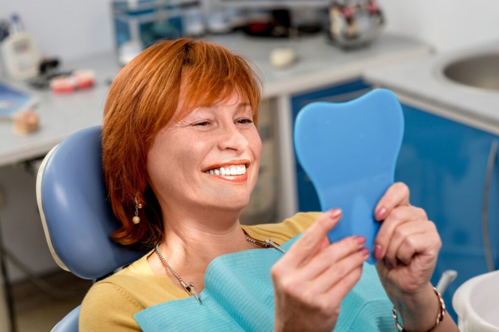 A woman looking at her new smile in the mirror