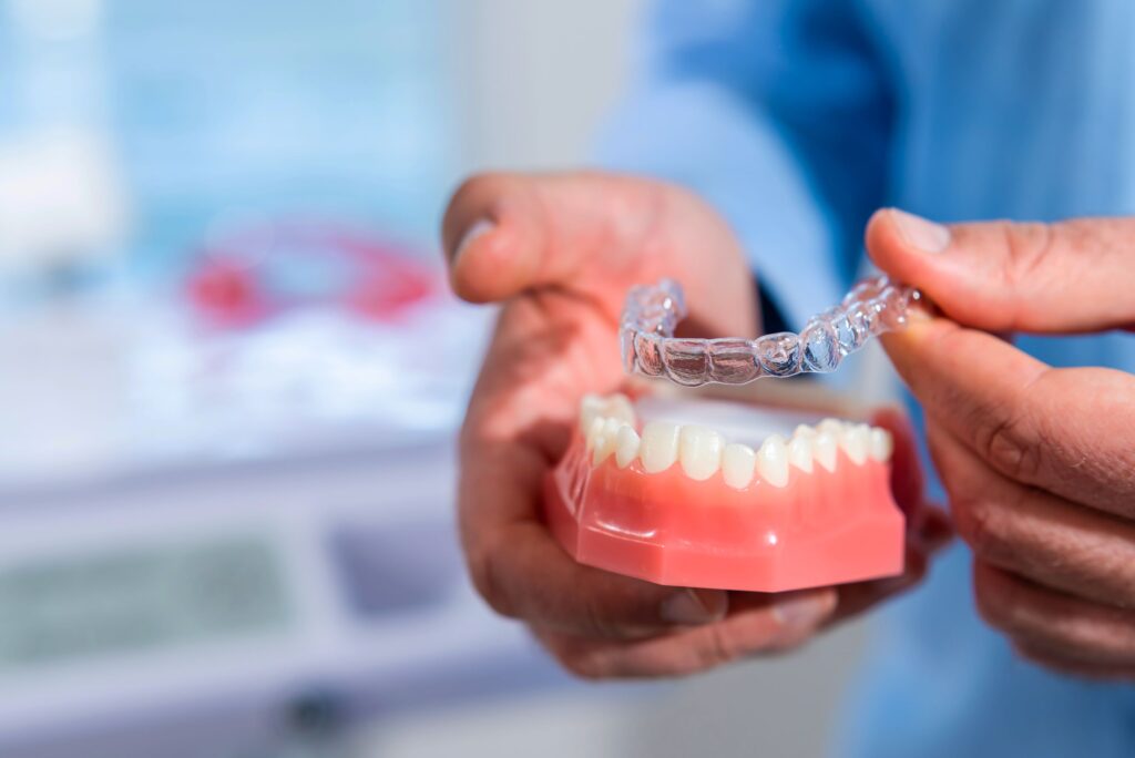 Hands placing Invisalign over arch of model teeth