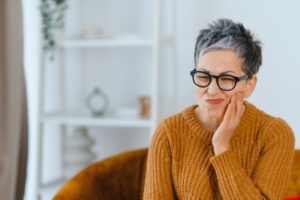 Woman holding side of face in pain from toothache.