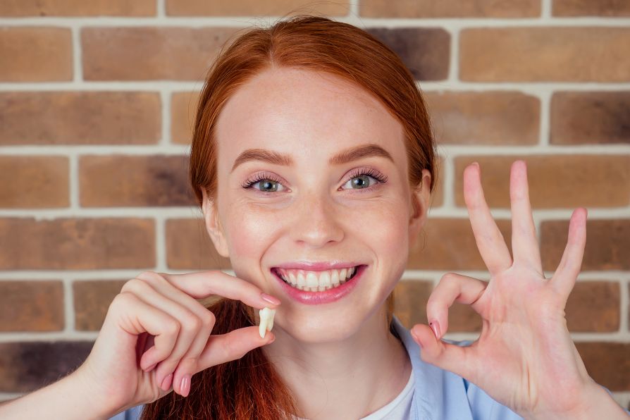A happy woman holding an extracted tooth
